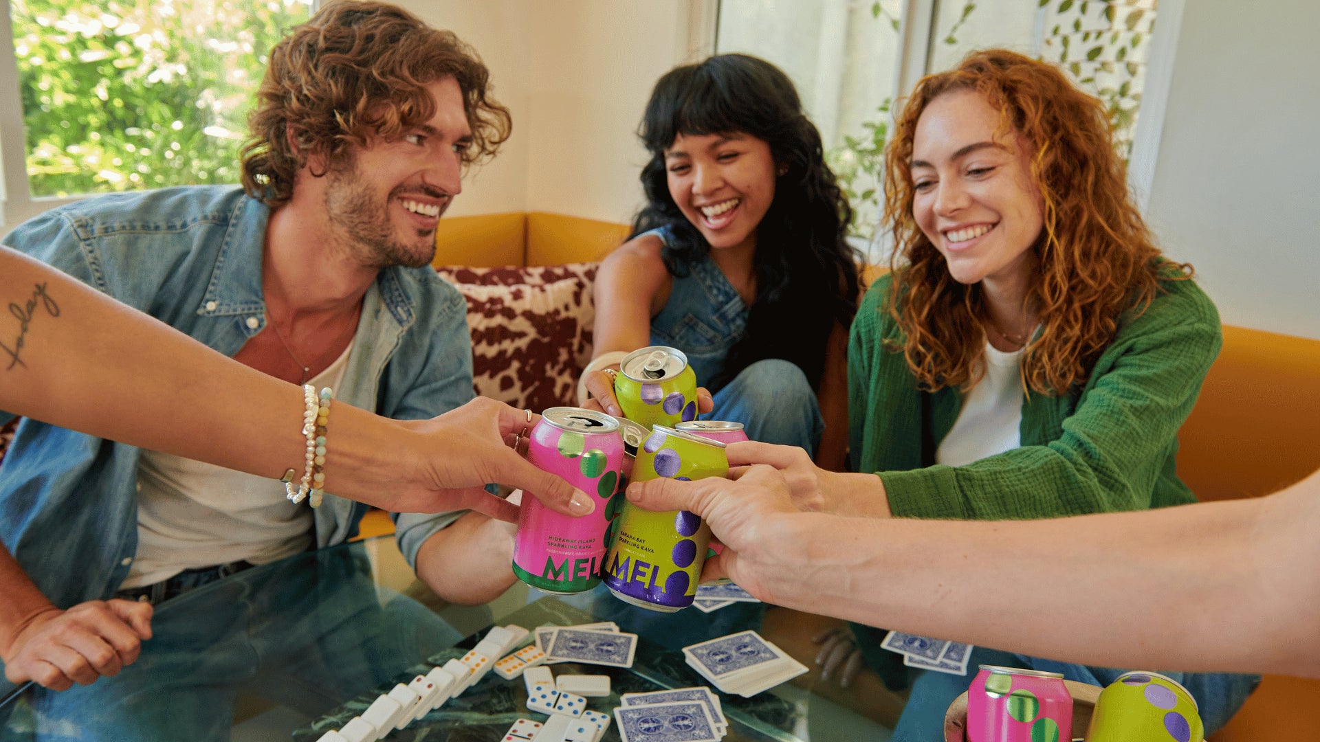 Friends toasting with Melo sparkling kava cans during a game night.