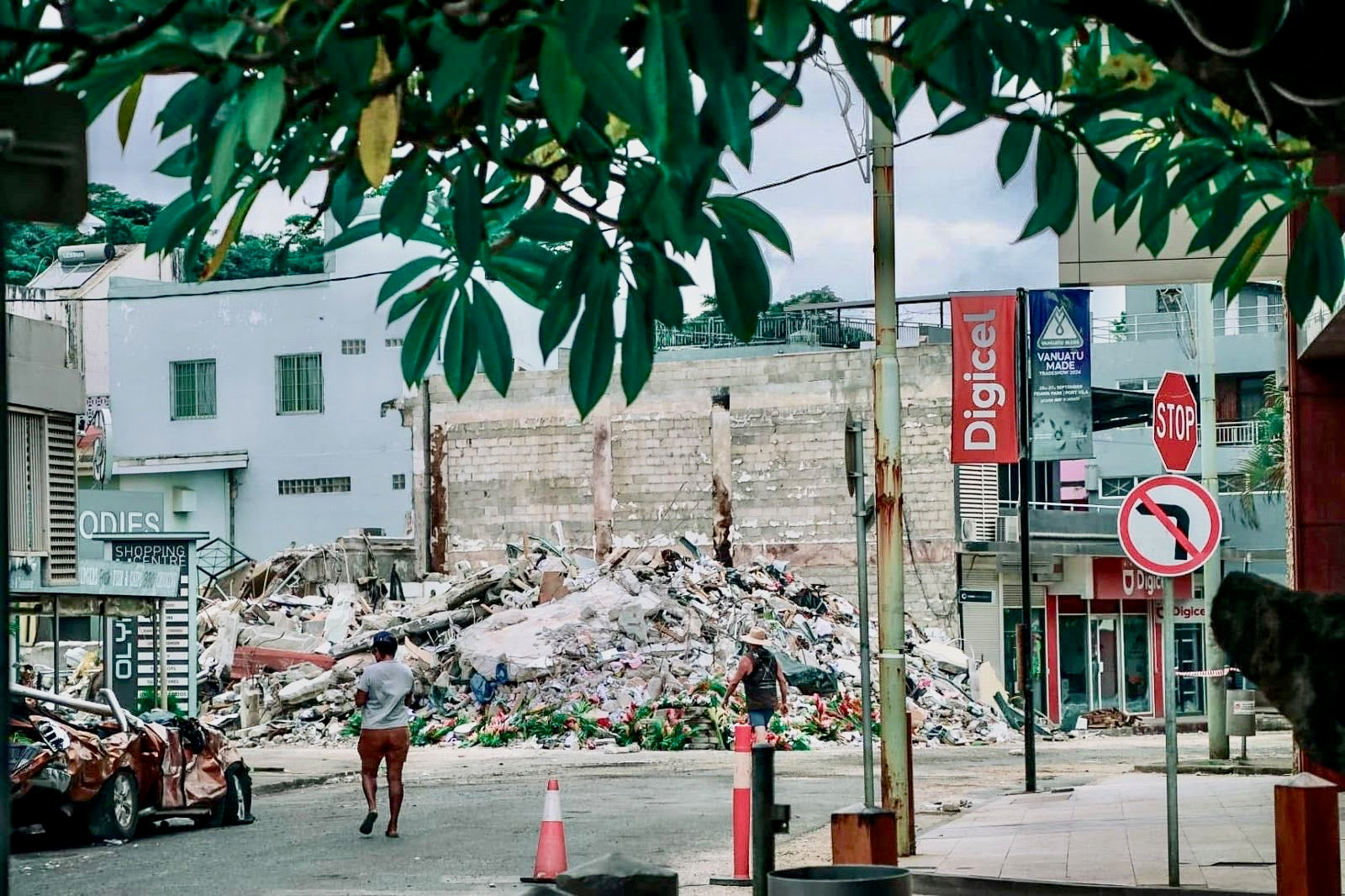 A street in Vanuatu with rubble and damaged buildings. Reflects community resilience and efforts to rebuild after devastation